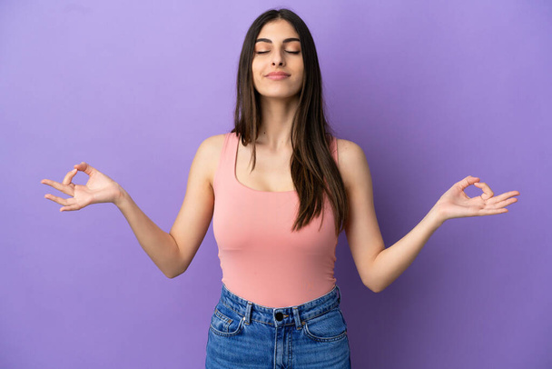Young caucasian woman isolated on purple background in zen pose - Фото, изображение