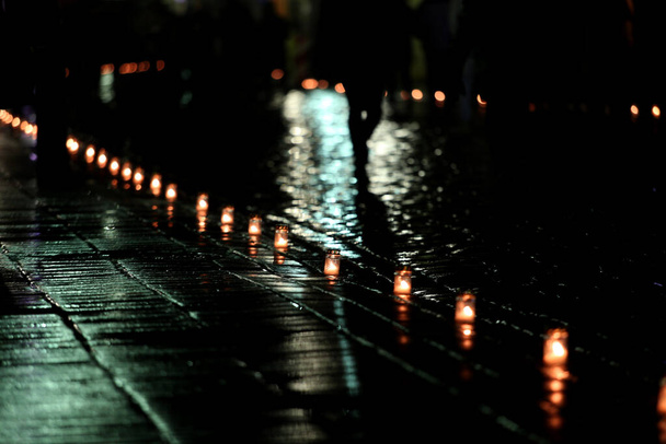 Płomień świecy z abstrakcyjnym tłem bokeh podczas deszczu w mieście. Nieszpory - Zdjęcie, obraz