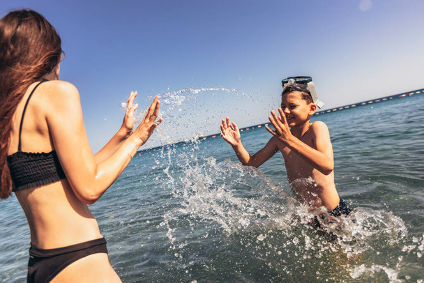 Брат и сестра играют на пляже в жаркий день летних каникул
. - Фото, изображение
