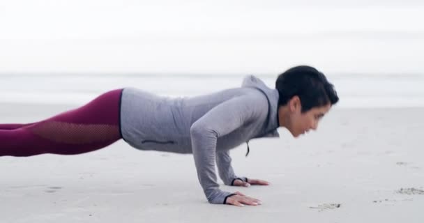 4k Videoaufnahmen einer attraktiven jungen Sportlerin, die Liegestütze macht, während sie am Strand trainiert. - Filmmaterial, Video