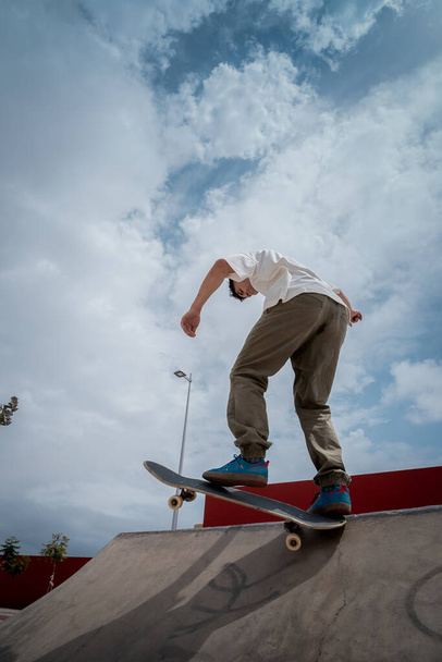 young skater on the top of a ramp in a skate park. vertical composition - Fotó, kép