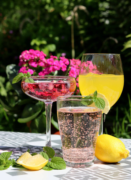 Refreshing summer cocktails on a garden table. Close up photo of glasses with various drinks. Party in a garden.  - Fotó, kép