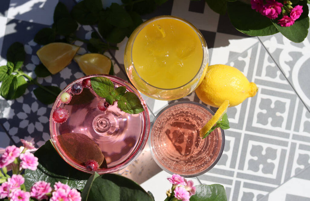 Mango, aardbeiencocktails en rozenlimonade op een tuintafel. Zomer cocktails close-up foto. Verfrissende drankjes in verschillende glazen.  - Foto, afbeelding