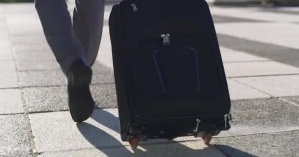 4k videofelvétel egy felismerhetetlen üzletemberről, aki a bőröndjével sétál a városban.. - Felvétel, videó