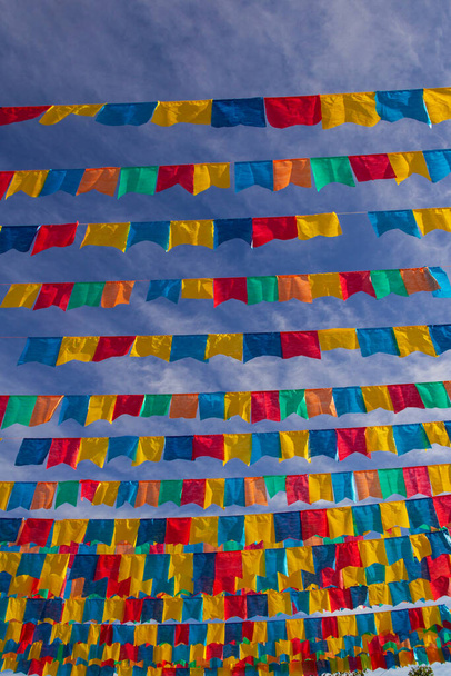 Varios tendederos con banderas de tela contra el cielo azul para la fiesta de junio - típico festival brasileño. "Cuadrilha". - Foto, Imagen