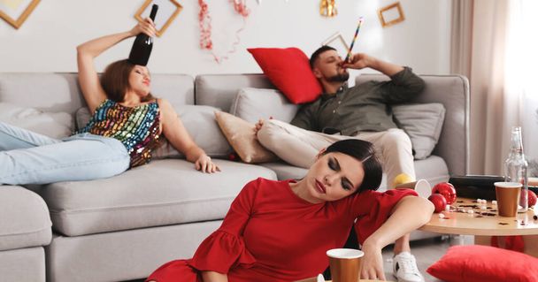 Young woman sleeping at table and her friends suffering from hangover in messy room after New Year party. Banner design - Фото, зображення