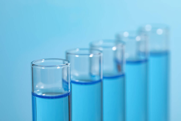 Δοκιμαστικοί σωλήνες με αντιδραστήρια σε ανοιχτό μπλε φόντο, κοντινό πλάνο. Εργαστηριακή ανάλυση - Φωτογραφία, εικόνα