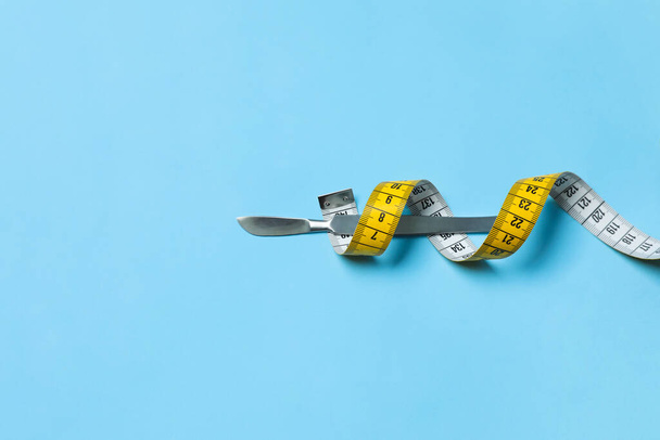 Scalpel and measuring tape on light blue background, top view with space for text. Weight loss surgery - Zdjęcie, obraz