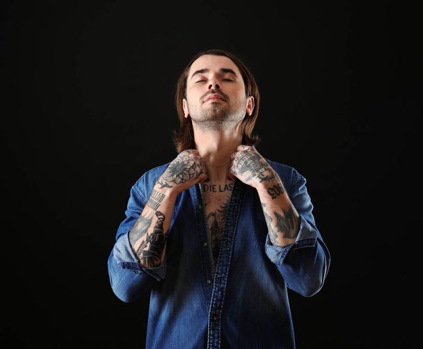 Young man with tattoos on body against black background - Фото, зображення