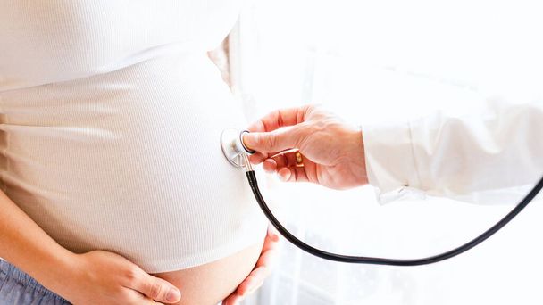 Pregnant consult doctor. Medical clinic for pregnancy consultant. Doctor examining pregnancy woman belly holding stethoscope. Concept of pregnancy, maternity, expectation for baby birth - Foto, Imagen