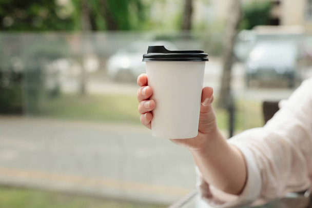 Woman holding paper takeaway cup outdoors, closeup with space for text. Coffee to go - Zdjęcie, obraz