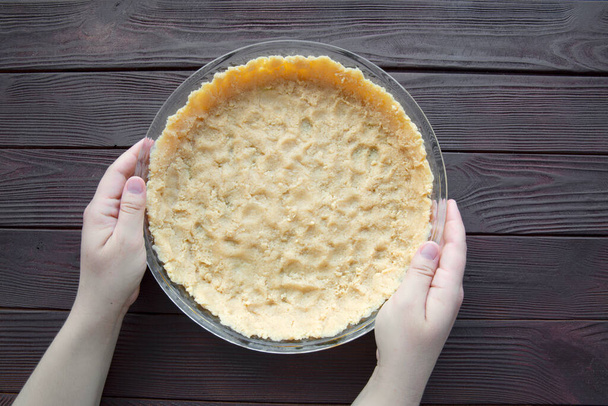 Pie or tart preparation. Female hands hold raw dough wooden table, top view.  - Valokuva, kuva