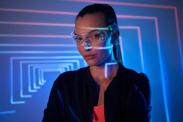 Beautiful young woman in futuristic glasses looking at camera - Фото, изображение