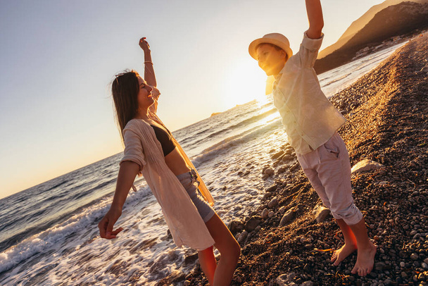 Брат и сестра веселятся на пляже. Дети танцуют на пляже.  - Фото, изображение