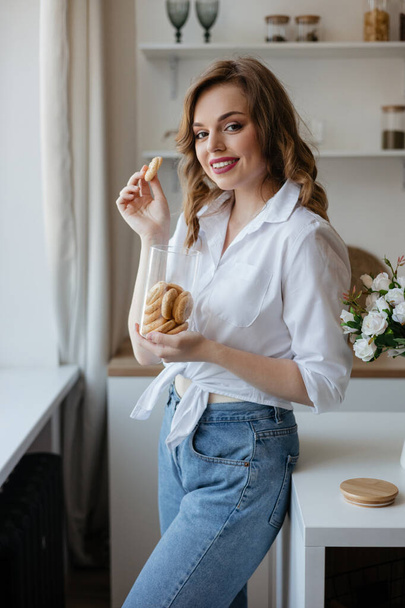 Pretty girl eating cookies in the kitchen. High quality photo - Фото, зображення