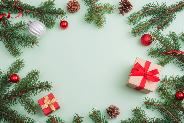 Vánoční dekorace, dárkové krabice, jedlové větve, cetky a borové šišky na světle zeleném pozadí. Horní pohled, plochá poloha, kopírovací prostor. - Fotografie, Obrázek