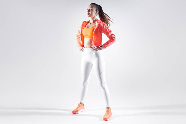 Повна довжина красивої молодої жінки в спортивному одязі, що стоїть на білому тлі
 - Фото, зображення