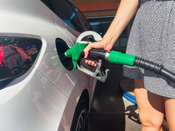 A woman filling up her car at a gas station. - Zdjęcie, obraz
