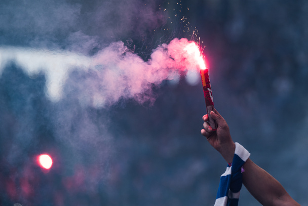 Οπαδός ποδοσφαίρου καίει φωτοβολίδα στο χέρι με κασκόλ στο γήπεδο - Φωτογραφία, εικόνα