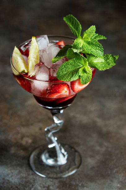 Fresh fruit cocktail with strawberry, mint and  lime in glass on dark  background. Summer cold drink or alcohol cocktail - Photo, image