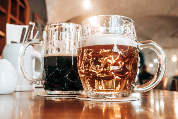 Two mugs of white and dark beer in pub. High quality photo - Φωτογραφία, εικόνα