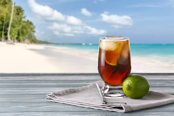 Egy pohár ízletes Cuba Libre koktél az asztalon trópusi üdülőhelyen - Fotó, kép
