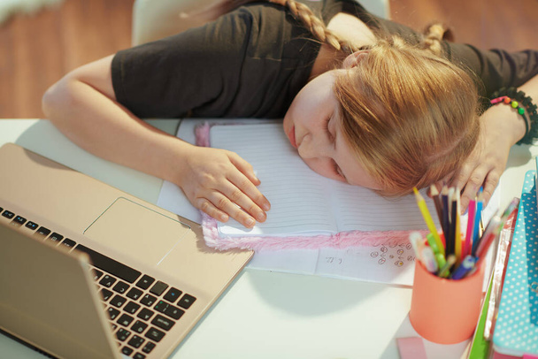 tired modern child in grey shirt with laptop and workbook sleeping at home in sunny day. - Фото, изображение