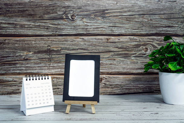 White September 2022 calendar on wooden desk with paper frame and potted plant. 2022 new year concept. Copy space. - Foto, imagen