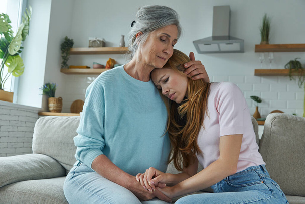 Senior woman consoling her sad daughter while sitting on the couch together - Φωτογραφία, εικόνα