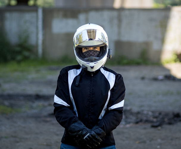 Young pretty female motorcyclist with full face helmet standing with full protective gear on - 写真・画像