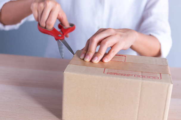 female hand use scissors open parcel box - Foto, Imagen