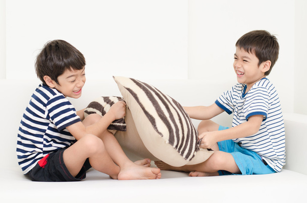 Kis testvér fiú játék harcok a kanapé párna - Fotó, kép