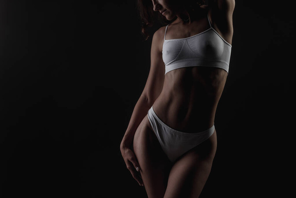 body shape of a sporty fitness girl studio photo on a dark background, the concept of sports and healthy eating - Photo, image