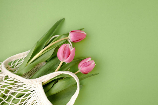 spring flat lay with string bag and tulips isolated on green. - Valokuva, kuva