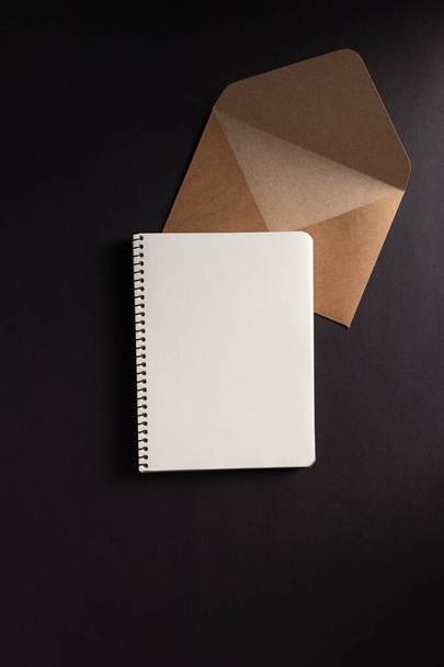 Paper notebook or notepad and envelope at black background texture. Creative idea concept - 写真・画像