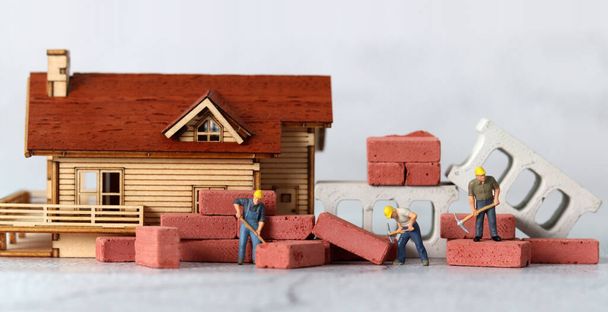 Miniaturarbeiter reparieren Häuser. Miniaturmenschen und Geschäftskonzept. - Foto, Bild
