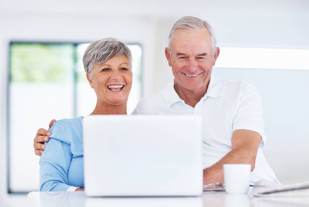 Glücklich reifes Paar lächelt, während es Laptop zu Hause benutzt. - Foto, Bild