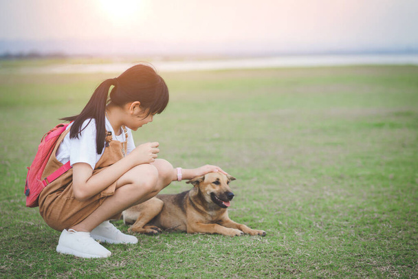 A kislány gyengéden és barátságosan simogatja kutyáját, szeretetet és gondoskodást mutat kedvtelésből tartott állatok iránt. - Fotó, kép
