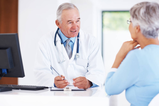 Mature doctor discussing medical report with female patient. - Foto, Bild