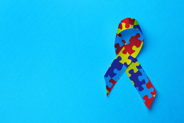 World Autism Awareness Day. Colorful puzzle ribbon on turquoise background, top view with space for text - Foto, imagen