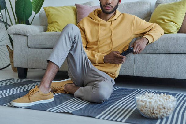 Close-up of young African man playing video games while sitting on the floor at home - Photo, image