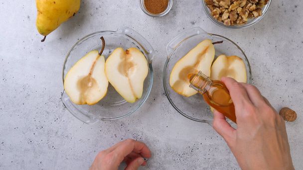 Gebakken peren met walnoten, honing en kaneel, close-up op rustieke achtergrond, perfect ontbijt of dessert, platte lay, vrouwenhanden - Foto, afbeelding