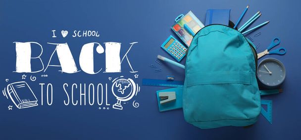 Backpack with stationery and text BACK TO SCHOOL on blue background - 写真・画像