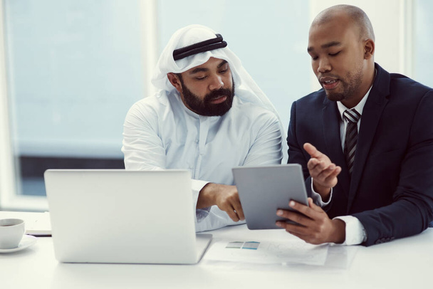 два бізнесмени, використовуючи цифровий планшет і ноутбук, обговорюючи в сучасному офісі
. - Фото, зображення
