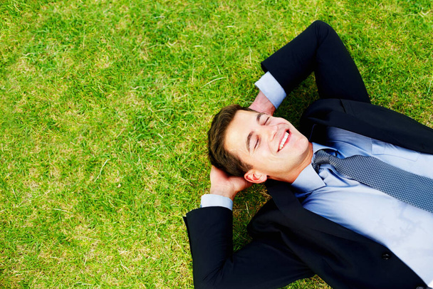 Fiatal férfi üzleti végrehajtó alszik fű és mosolygós - Copyspace. - Fotó, kép