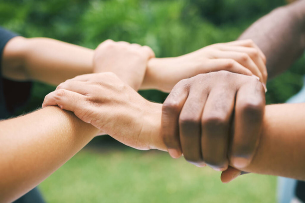 Hands holding wrists outside in nature. A diverse group of people holding wrist as a concept of loyalty. Closeup of a multiethnic group holding wrists. - Foto, afbeelding