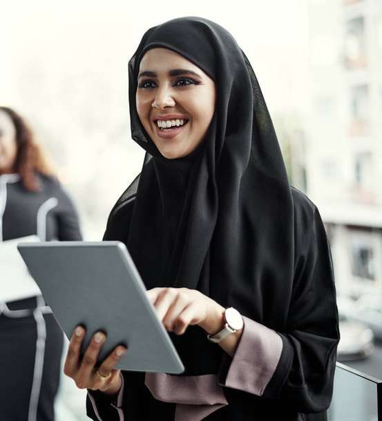 an attractive young businesswoman dressed in Islamic traditional clothing using a tablet on her office balcony. - Foto, Bild