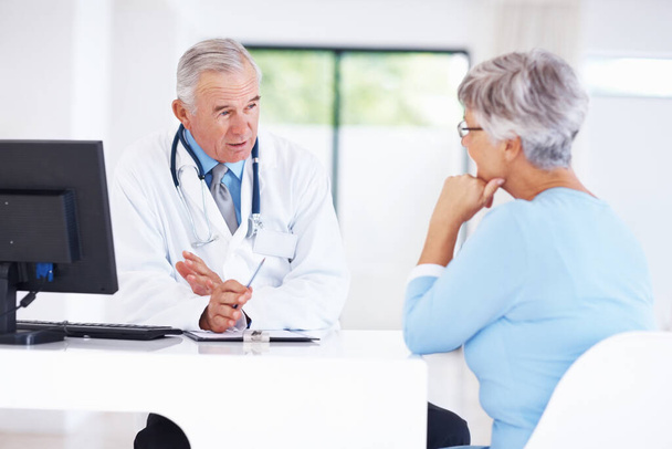 Confident mature doctor discussing medical report with female patient. - Foto, Imagem