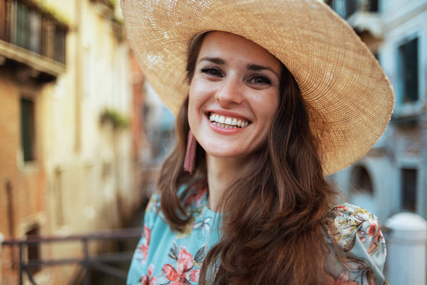 Portrait of smiling middle aged traveller woman in floral dress with hat having excursion in Venice, Italy. - Foto, Imagen