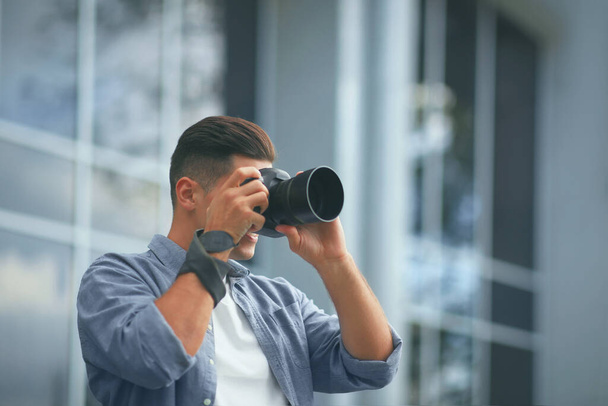 Photographer taking picture with professional camera on city street - Φωτογραφία, εικόνα